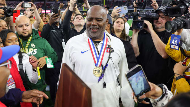 Duncanville (Texas) coach Reginald Sample holds up the UIL 6A Division I 2023 state championship trophy.