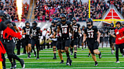 Louisville players running onto the field of L&N Stadium during pregame.
