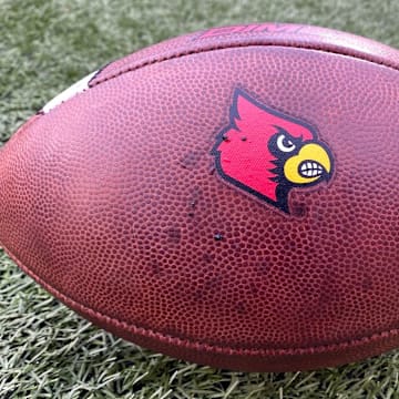 A football sporting the Louisville Cardinals logo