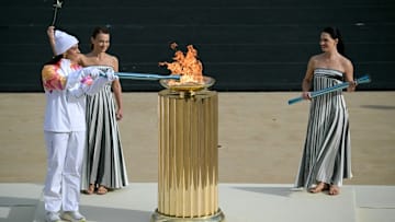 La waterpolista griega Eleni Xenaki (I) junto a la actriz griega Mary Mina (D), en su rol de sacerdotisa, en el encendido de la antorcha.