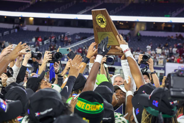 DeSoto coach Claude Mathis holds up the UIL (Texas) 6A Division II state championship trophy at AT&T Stadium in Dec. 2023.