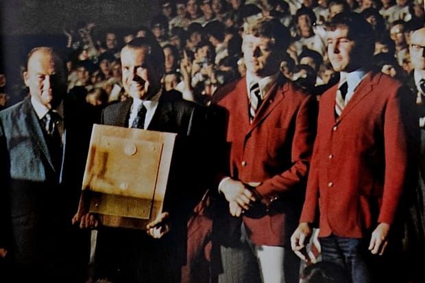 Jerry Murtaugh, right, stands with coach Bob Devaney and fullback Dan Schneiss as President Richard Nixon presents a plaque r