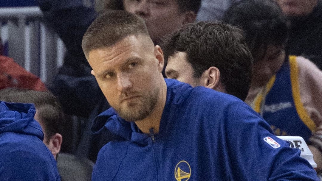 Feb 19, 2026; San Francisco, California, USA; New Golden State Warriors forward Kristaps Porzingis (with towel) watches the action against the Boston Celtics from the bench during the first quarter at Chase Center. Mandatory Credit: D. Ross Cameron-Imagn Images