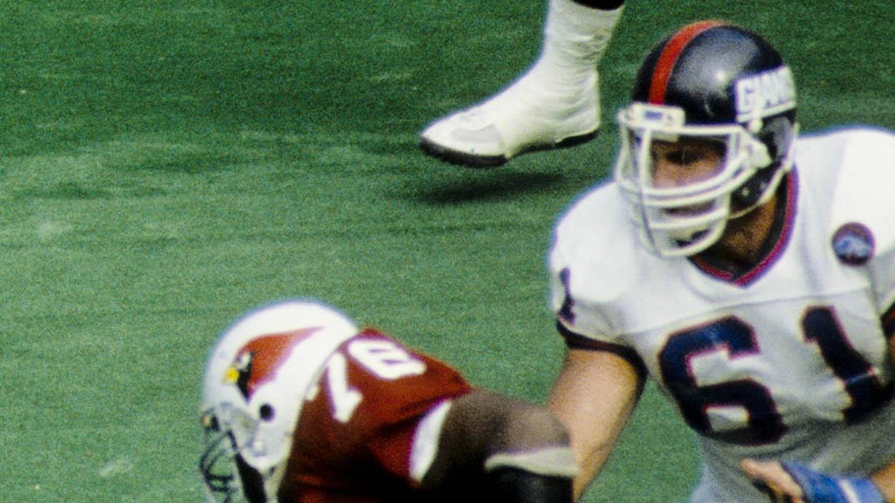 Oct 5, 1986; St. Louis, MO, USA; FILE PHOTO; New York Giants guard Chris Godfrey (61) attempts to protect quarterback Phil Simms (11) as he throws the ball under pressure from St. Louis Cardinals defensive ends Van Hughes (78) and Al Baker (60) at Busch Stadium.