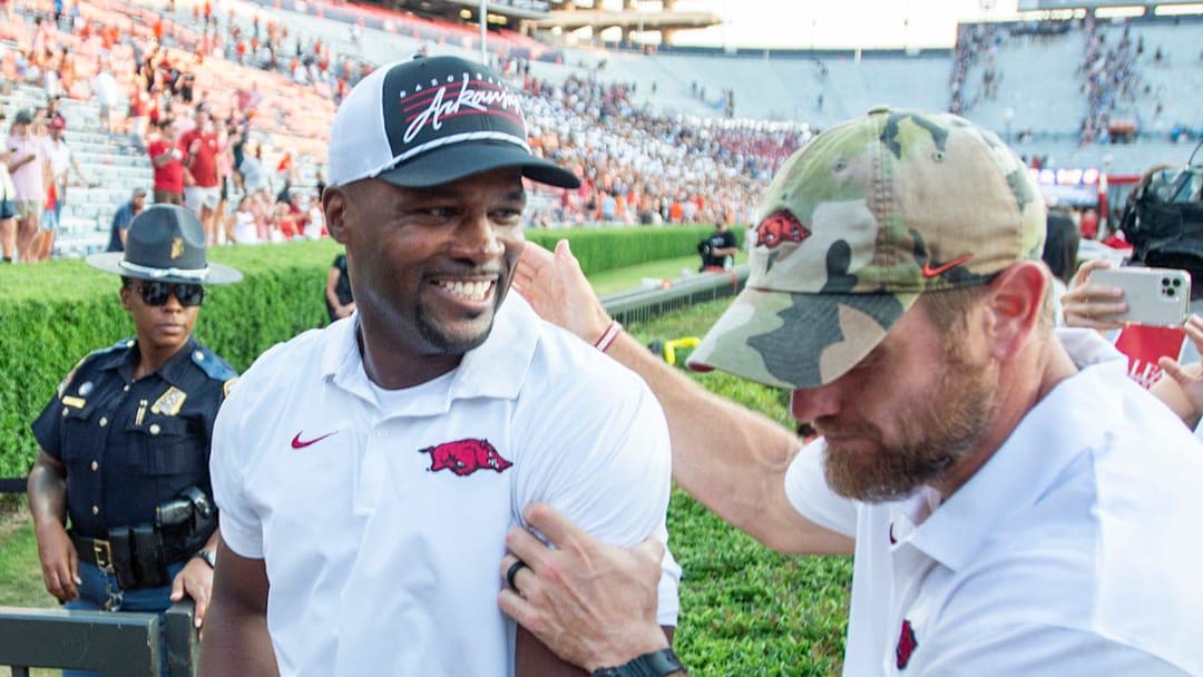 Arkansas Razorbacks defensive coordinator and former Auburn player and coach Travis Williams cheers with fans as he walks off the field