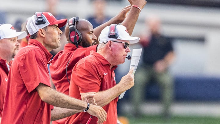 Arkansas Razorbacks coach Bobby Petrino using play sheet to cover crowd noise on microphone against UAPB in Little Rock.