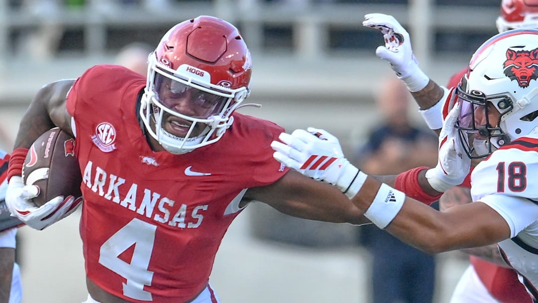 Arkansas Razorbacks running back Mike Washington stiff-arms an Arkansas State Red Wolves defender at War Memorial Stadium in Little Rock, Ark.