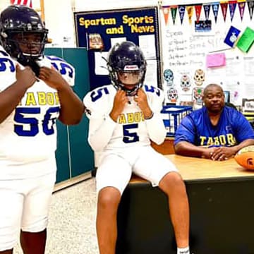 Mount Tabor head football coach Tiesuan Brown (seated) with three of his players who are modeling the team's new white uniforms for the 2024 season.