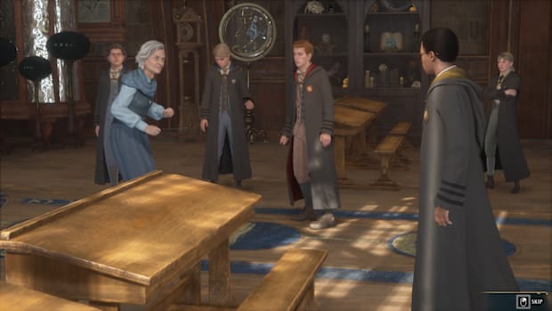 Hogwarts Legacy screenshot. Students for various houses standing in a classroom while the teacher looks around them.