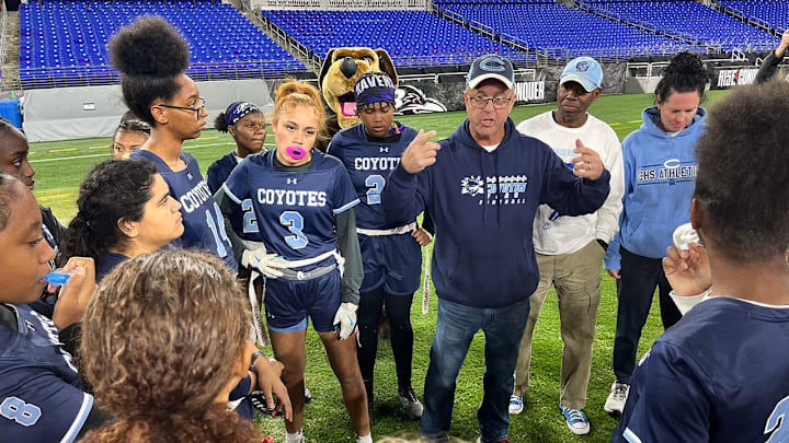 Clarksburg girls flag football head coach K.C. Landefeld speaks with his team during halftime of Friday's state championship game at M&T Bank Stadium.