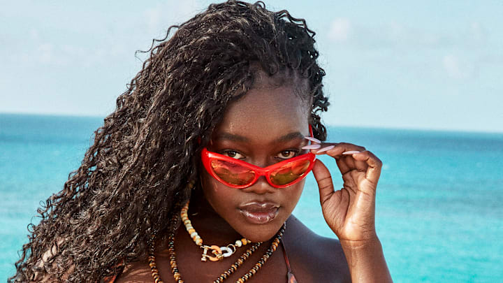 Achieng Agutu was photographed by Ben Watts in Bermuda. Suit by JMP The Label. Necklaces by Spicy Dan. Sunglasses by Le Specs.