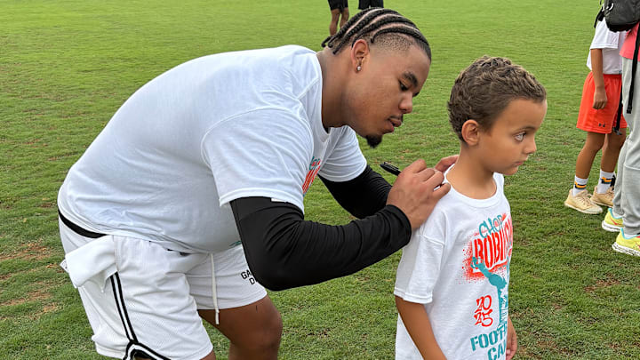 Current Miami Dolphin Chop Robinson, a Quince Orchard grad, signs the t-shirt of a young fan at his recent youth camp in Gaithersburg, Maryland. Current Miami Dolphin Chop Robinson, a Quince Orchard grad, signs the t-shirt of a young fan at his recent youth camp in Gaithersburg, Maryland.
