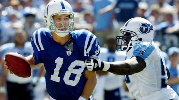 Former Colts quarterback Peyton Manning (blue jersey) tries to escape a sack to make a throw down the field.