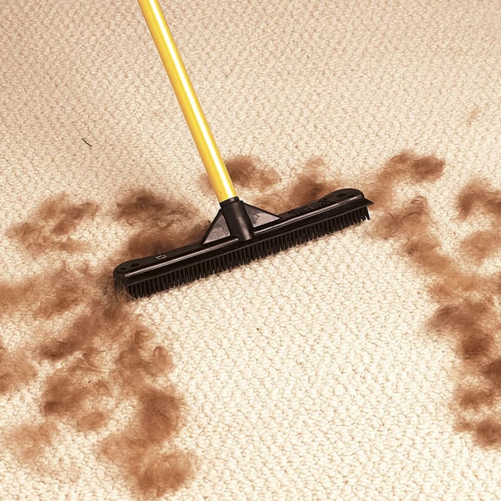 FURemover Pet Hair Remover Carpet Rake used on carpet surrounded by pet hair.