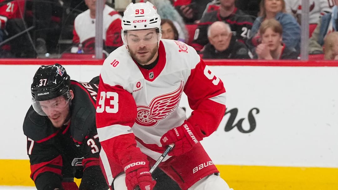 Dec 27, 2025; Raleigh, North Carolina, USA;  Detroit Red Wings right wing Alex Debrincat (93) tries to control the puck against the check by Carolina Hurricanes right wing Andrei Svechnikov (37) during the second period at Lenovo Center. 