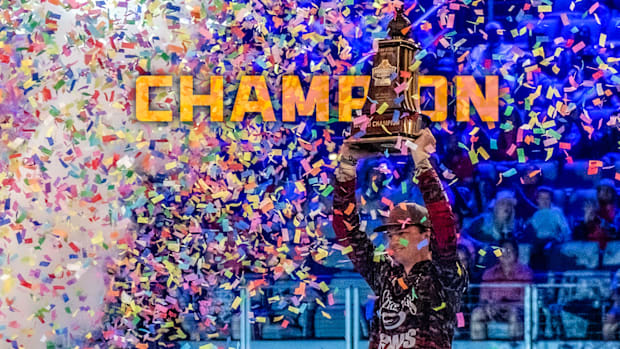 Easton Fothergill hoisting the Bassmaster Classic trophy overhead in celebration.