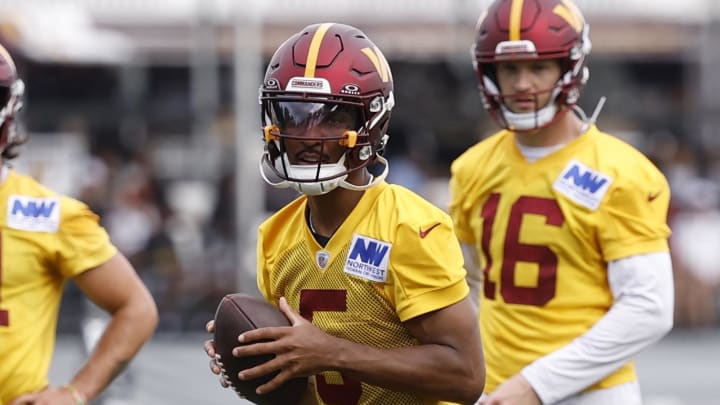 Jul 26, 2024; Ashburn, VA, USA; Washington Commanders quarterback Jayden Daniels (5) prepares to pass the ball as Commanders quarterbacks Sam Hartman (11) and Jeff Driskel (16) look on during day three of training camp at Commanders Park. Mandatory Credit: Geoff Burke-USA TODAY Sports