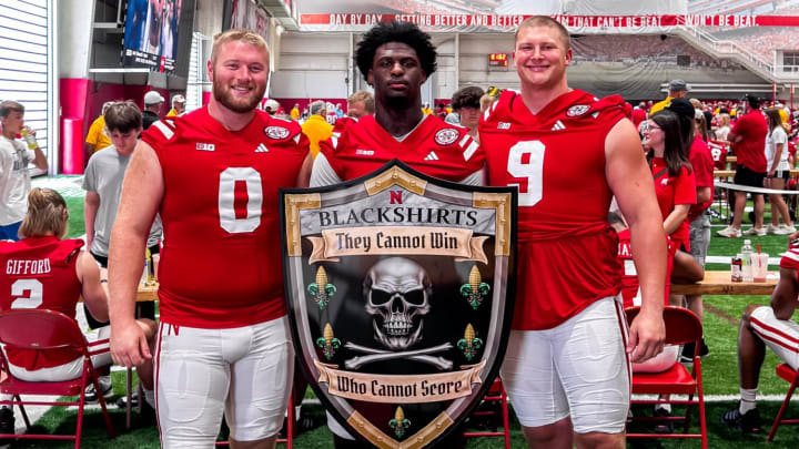 Nash Hutmacher, Jimari Butler and Ty Robinson pose with the Blackshirts shield during 2024 Nebraska football Fan Day.