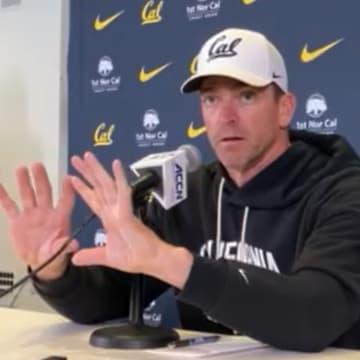 Justin Wilcox shows where Jaron-Keawe Sagapolutele should receive a shotgun snap
