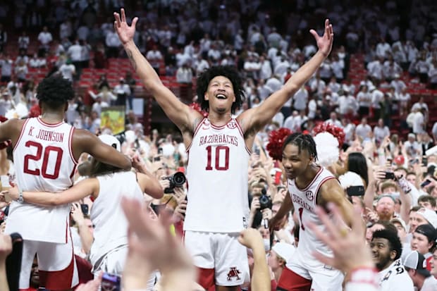 Arkansas forward Jaylin Williams stands on a table celebrating a win over No. 1 Auburn in Bud Walton Arena.