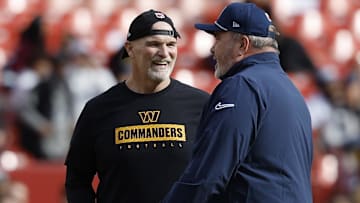 Washington Commanders head coach Dan Quinn (L) talks with former Dallas Cowboys head coach Mike McCarthy (R) on the field during warmup prior to their game at Northwest Stadium.