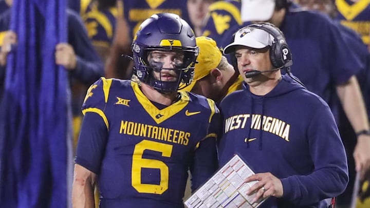 Oct 19, 2024; Morgantown, West Virginia, USA; West Virginia Mountaineers head coach Neal Brown talks with quarterback Garrett Greene (6) before a play during the second quarter against the Kansas State Wildcats at Mountaineer Field at Milan Puskar Stadium. Mandatory Credit: Ben Queen-Imagn Images