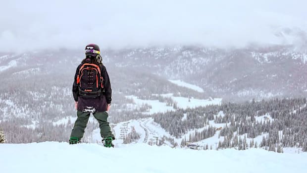 Snowboarder stops before heading down the mountain