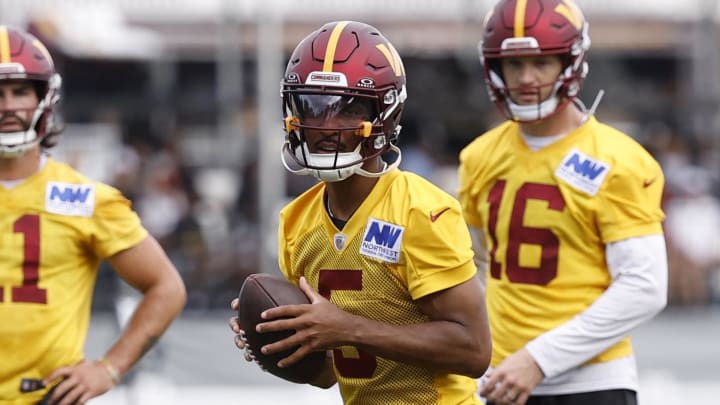 Jul 26, 2024; Ashburn, VA, USA; Washington Commanders quarterback Jayden Daniels (5) prepares to pass the ball as Commanders quarterbacks Sam Hartman (11) and Jeff Driskel (16) look on during day three of training camp at Commanders Park. Mandatory Credit: Geoff Burke-USA TODAY Sports