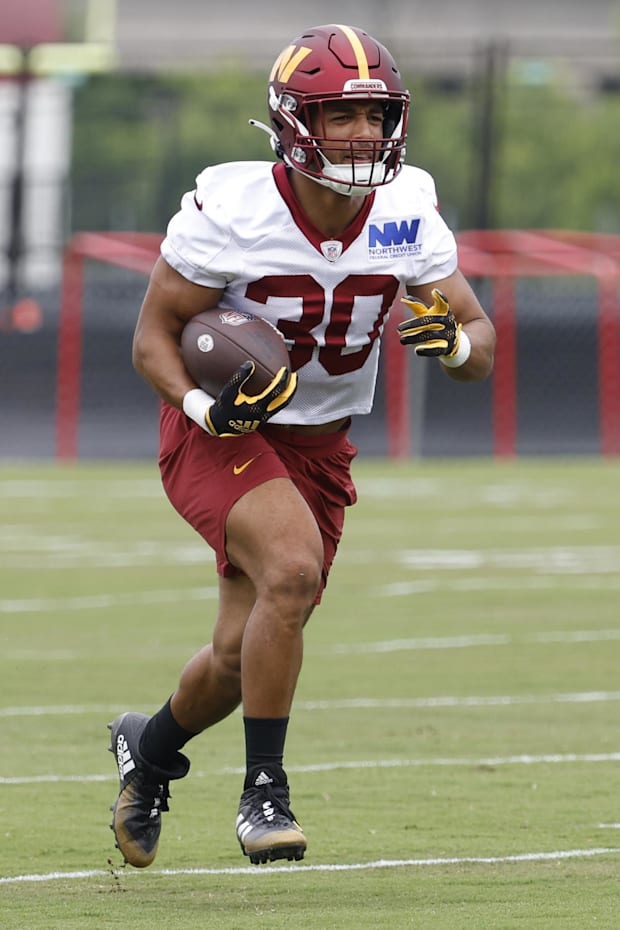 Washington Commanders running back Austin Ekeler carries the ball during OTA workouts
