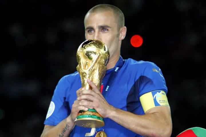 Italy defender (5) Fabio Cannavaro kisses the World Cup trophy while surrounded by teammates.