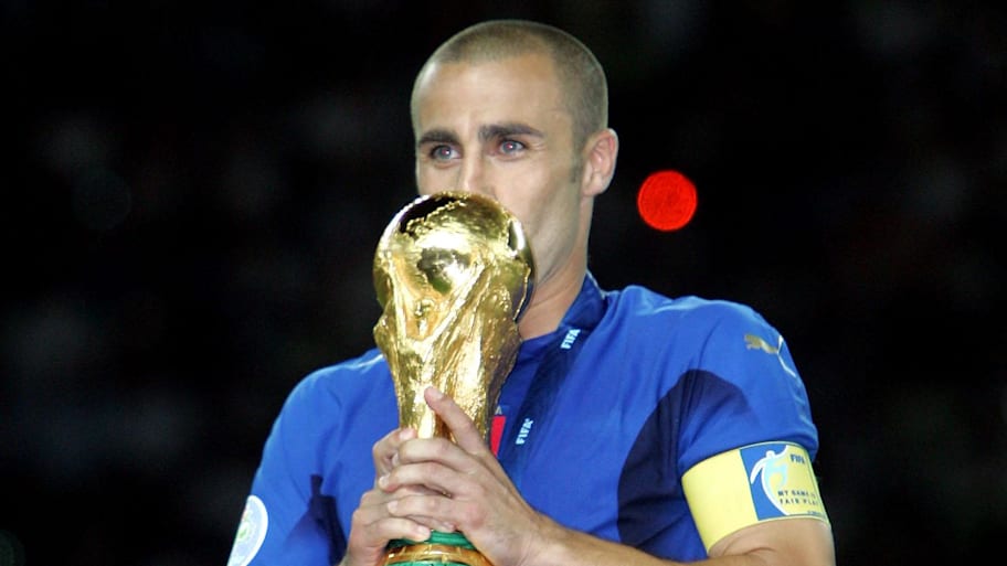 Italy defender (5) Fabio Cannavaro kisses the World Cup trophy while surrounded by teammates.