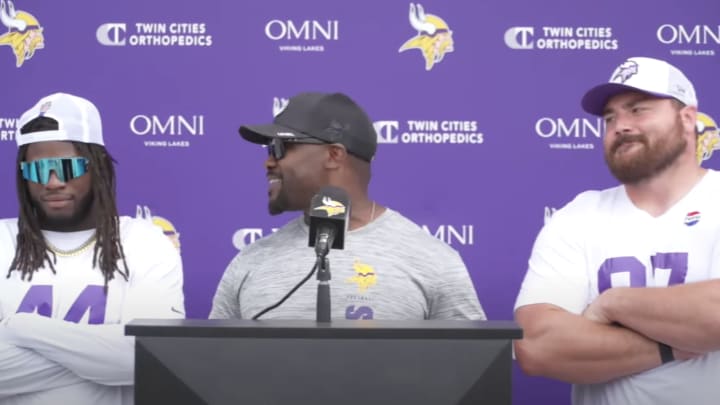 Vikings players Josh Metellus and Harrison Phillips stand behind defensive coordinator Brian Flores.