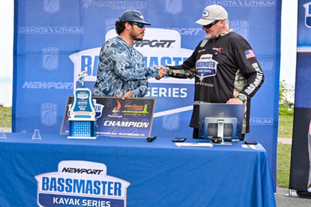 Bailey Eigbrett shaking hands with a tournament official as he accepts the trophy for the Bassmaster Kayak event