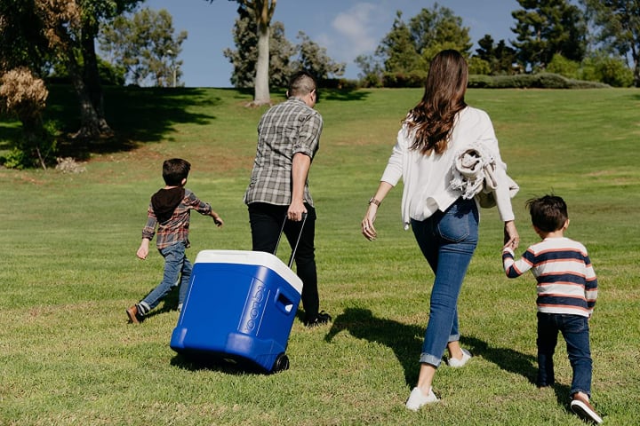 Family walking up a grassy field with an Igloo Profile cooler in tow.