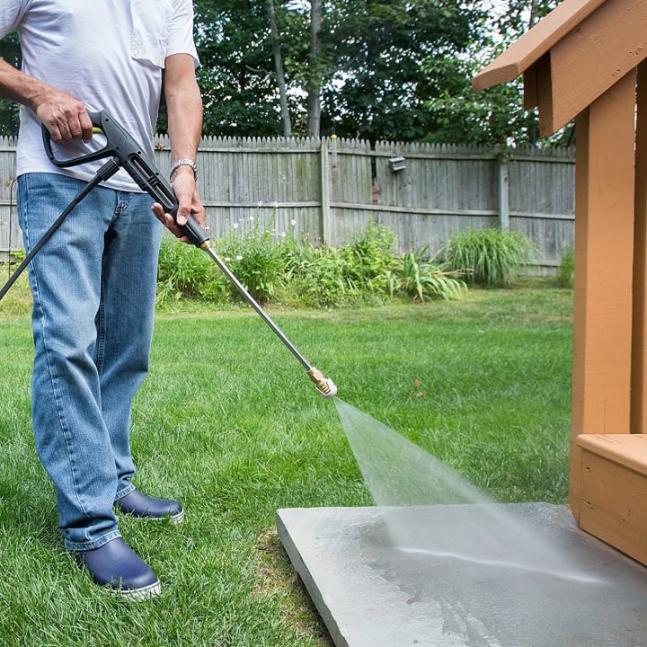Man pictured from waist-down using a Sun Joe pressure washer.