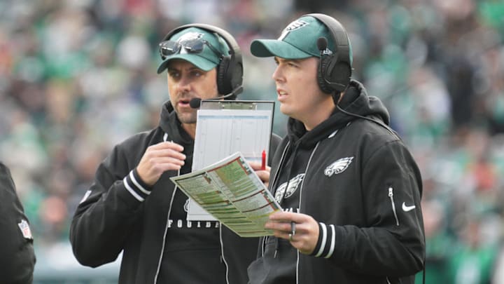 Eagles coaches Kevin Patullo and Kellen Moore confer on the sideline.