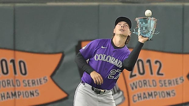 Colorado Rockies outfielder Jordan Beck catches a ball wearing a purple jersey.