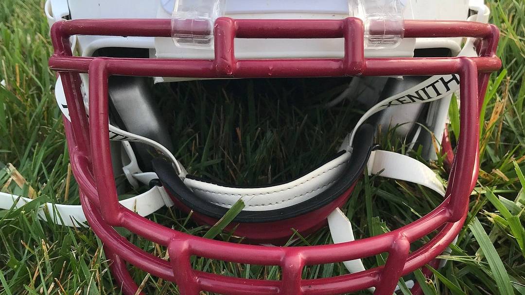 A high school football helmet resting in the grass. A high school football helmet resting in the grass.
