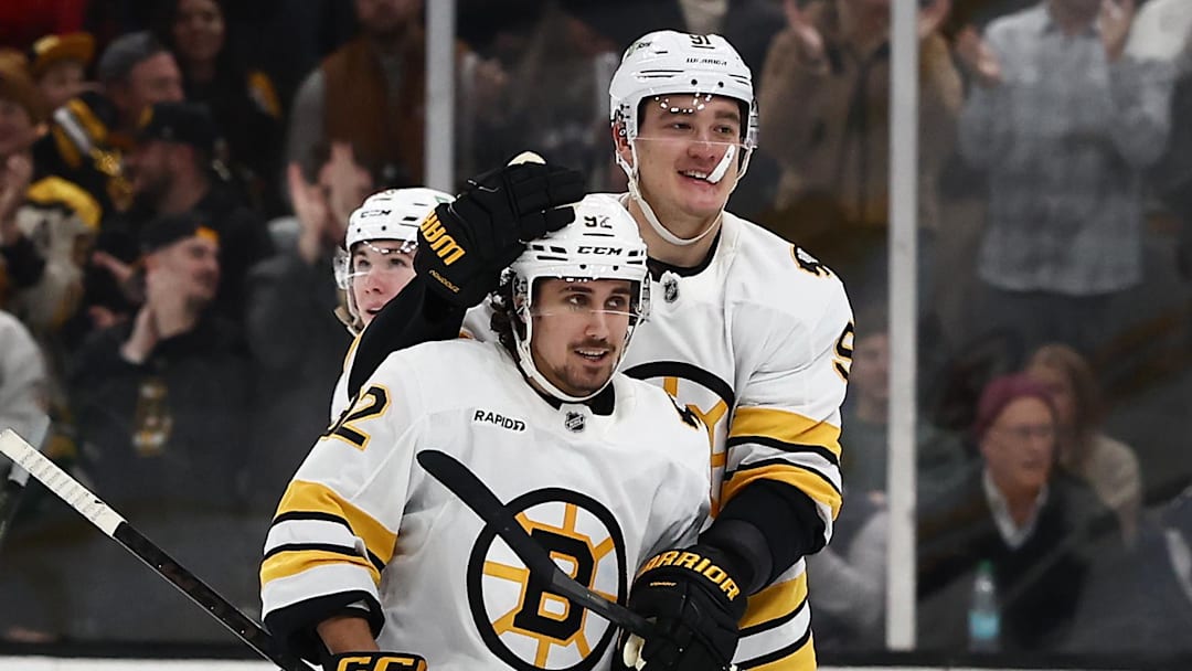 Jan 10, 2026; Boston, Massachusetts, USA; As a member of the ice crew picks up hats, Boston Bruins center Marat Khusnutdinov (92) is congratulated by defenseman Nikita Zadorov (91) after scoring his third goal of the game during the third period against the New York Rangers at TD Garden. Mandatory Credit: Winslow Townson-Imagn Images