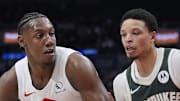 Toronto Raptors forward RJ Barrett controls the ball against Milwaukee Bucks guard Ryan Rollins.
