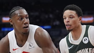 Toronto Raptors forward RJ Barrett controls the ball against Milwaukee Bucks guard Ryan Rollins.