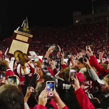 Surrounded by fans on the field, Nebraska players hoist the Freedom Trophy after their game against Wisconsin.