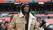 NFL legend Deion Sanders tries to keep a low profile as photographers swarm his on the sideline before an NFL football game at Huntington Bank Field, Dec. 7, 2025, in Cleveland, Ohio.