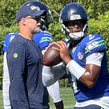 Seattle Seahawks quarterback Geno Smith prepares to throw while offensive coordinator Ryan Grubb looks on during a drill at training camp at the Virginia Mason Athletic Center.