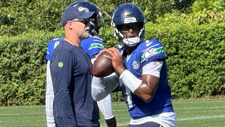 Seattle Seahawks quarterback Geno Smith prepares to throw while offensive coordinator Ryan Grubb looks on during a drill at training camp at the Virginia Mason Athletic Center.