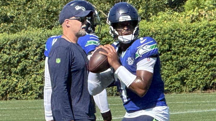 Seattle Seahawks quarterback Geno Smith prepares to throw while offensive coordinator Ryan Grubb looks on during a drill at training camp at the Virginia Mason Athletic Center.