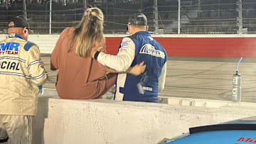 Michael McDowell helps Marissa Briscoe over the pit road wall at Darlington Raceway following Chase Briscoe's win in the Cook Out Southern 500.