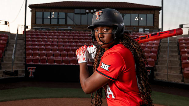 A softball player in a red jersey gets ready to swing a bat