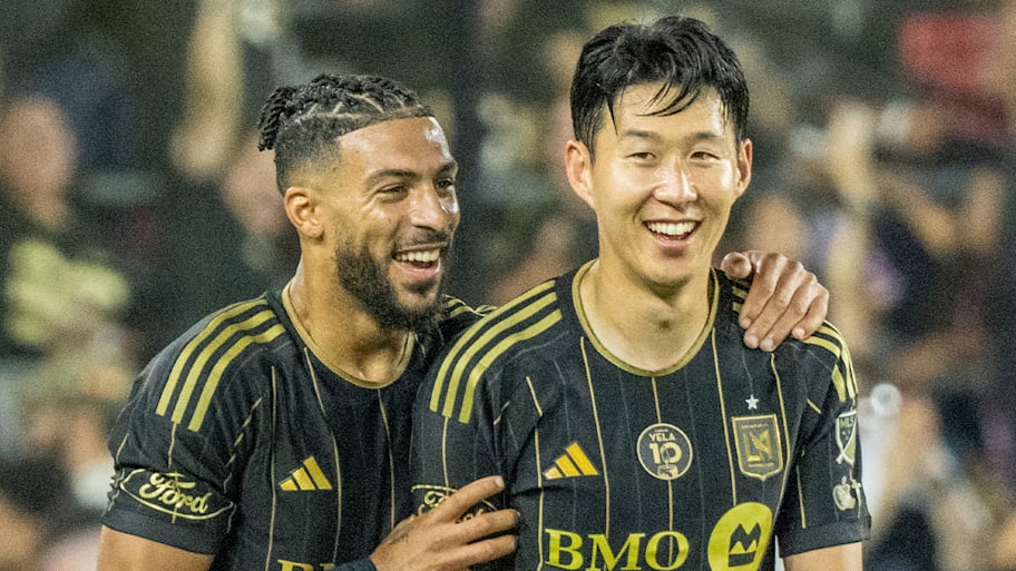 Denis Bouanga and Son Heung-min embracing and smiling. Both are wearing LAFC’s black strip with yellow pinstripes.