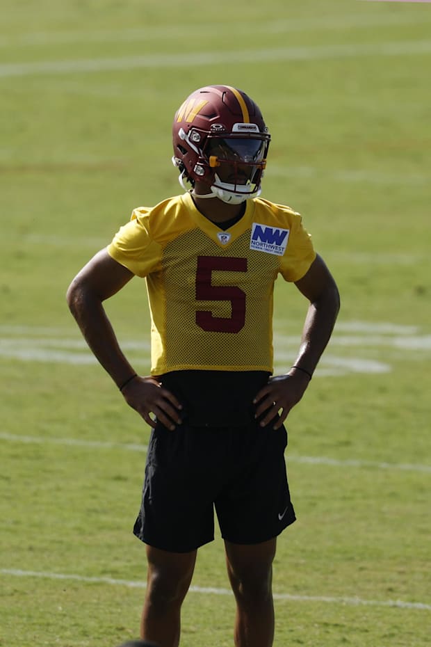 Washington Commanders quarterback Jayden Daniels stands on the field during practice